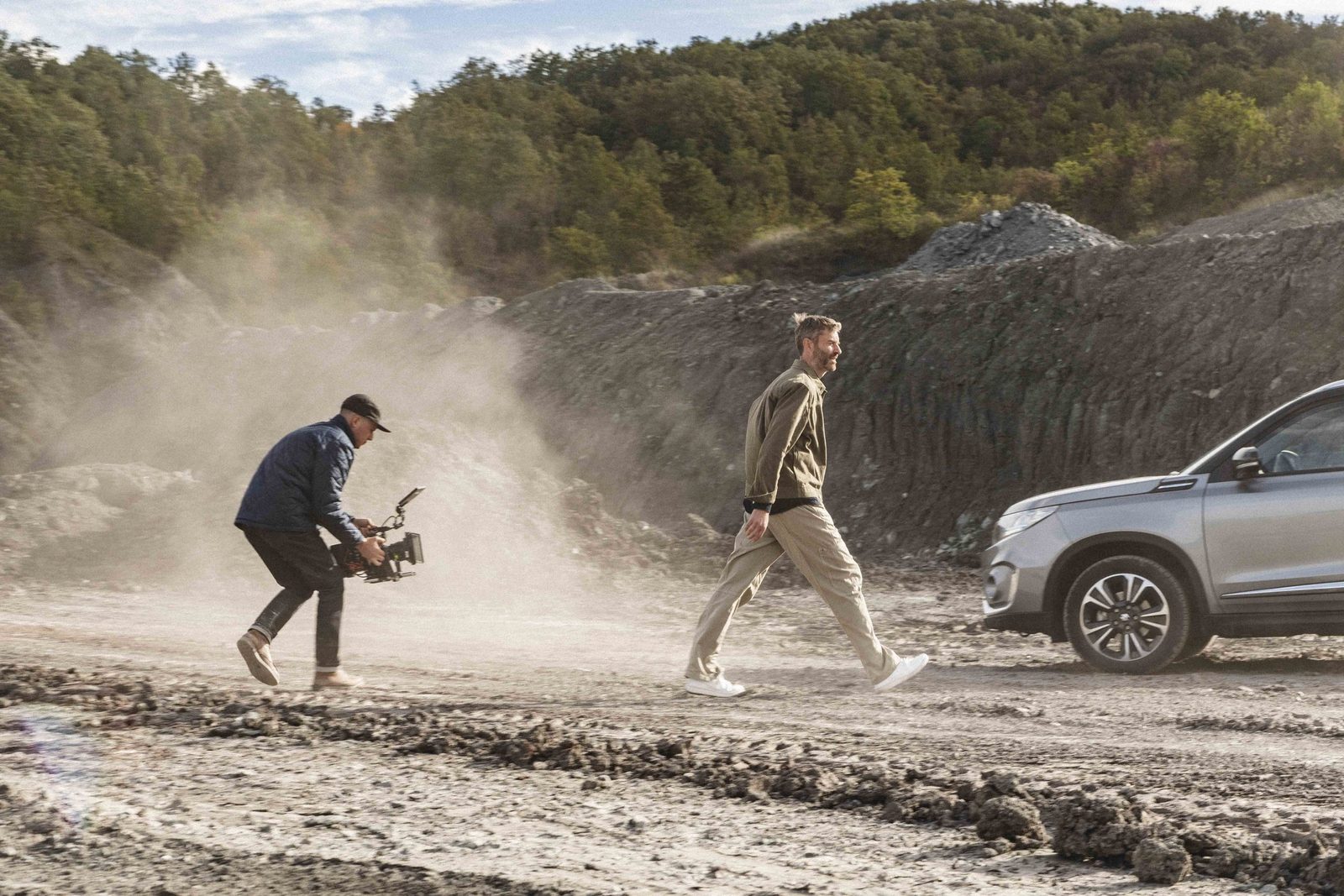 Filming a car commercial on a dirt road, camera operator running alongside