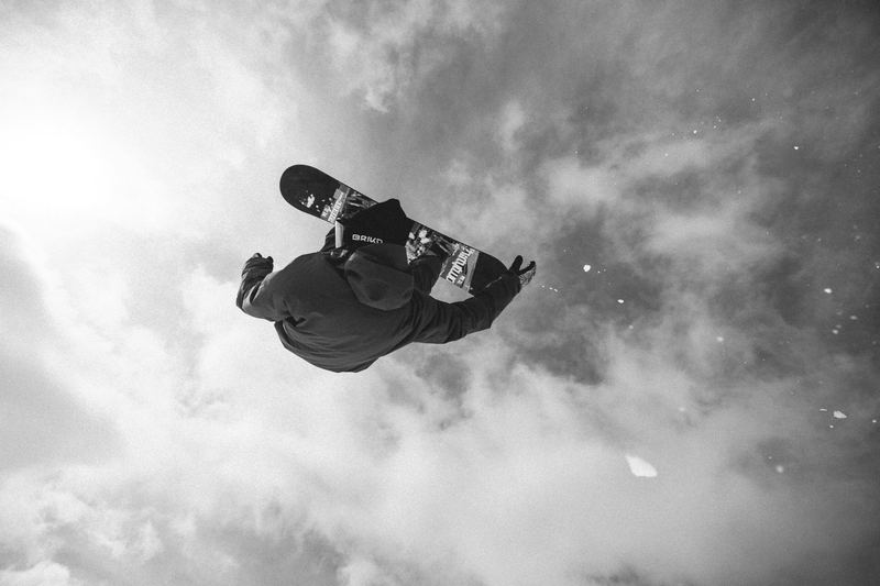 A snowboarder inverted mid-air against the clouds