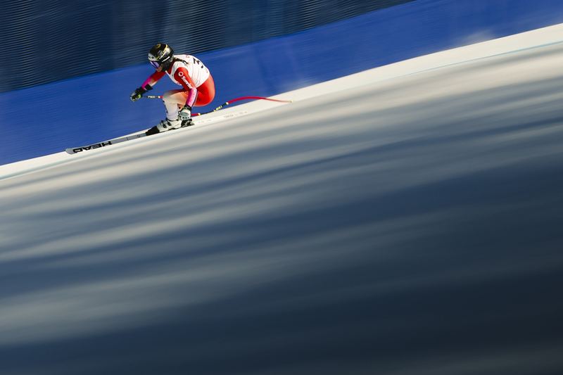 A downhill skier panned against blue safety netting