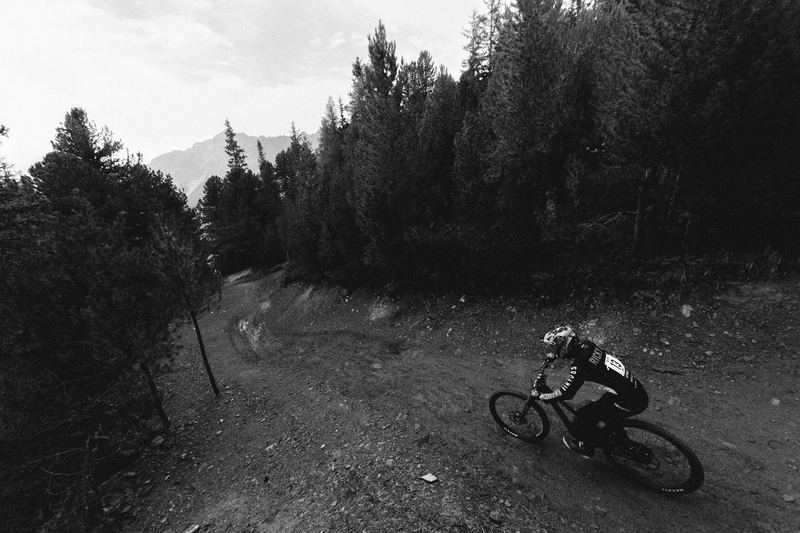 A mountain biker on a fire road through alpine woods