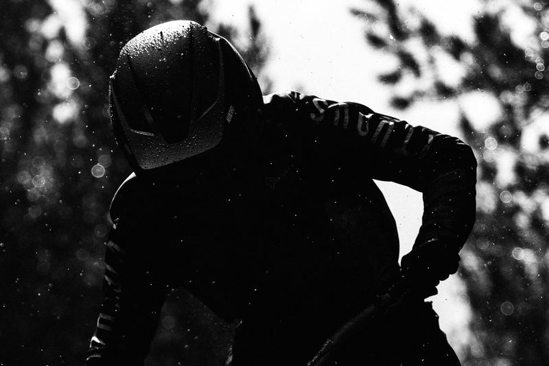 A rider in a full-face helmet backlit in the trees