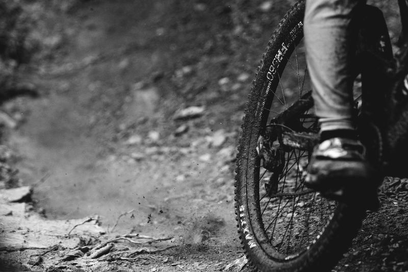 A bike wheel and the rider's foot on loose rock