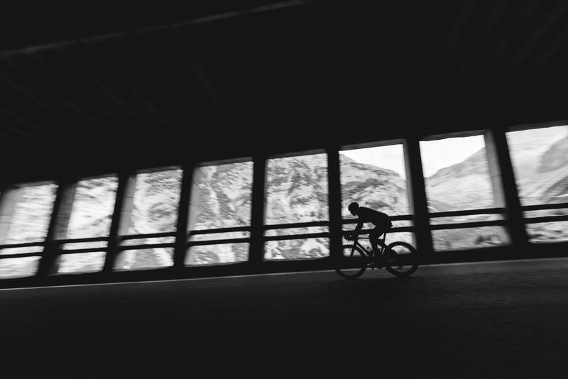 A cyclist riding through the arches of a mountain gallery