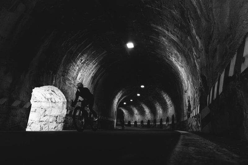 A cyclist riding out of a lit tunnel