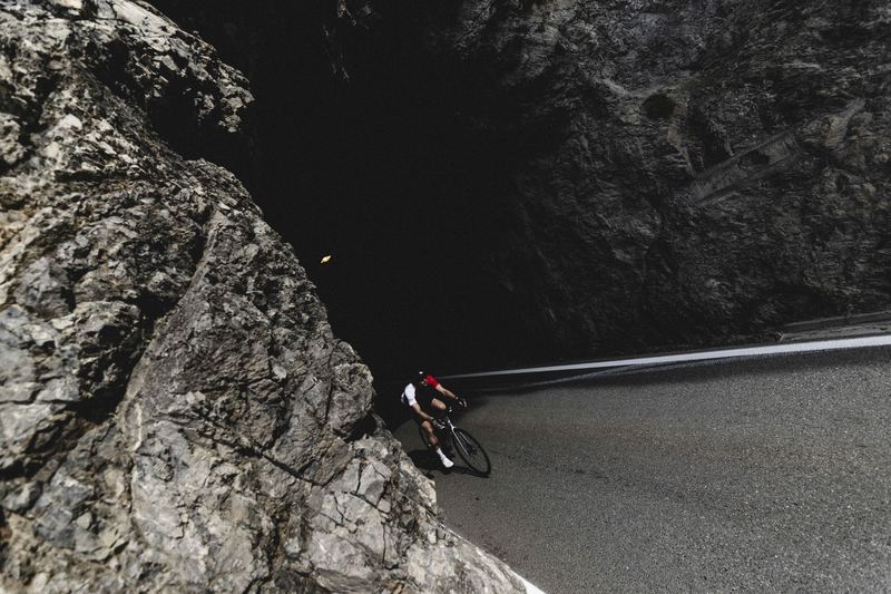 A cyclist on a pass road cut into the rock face