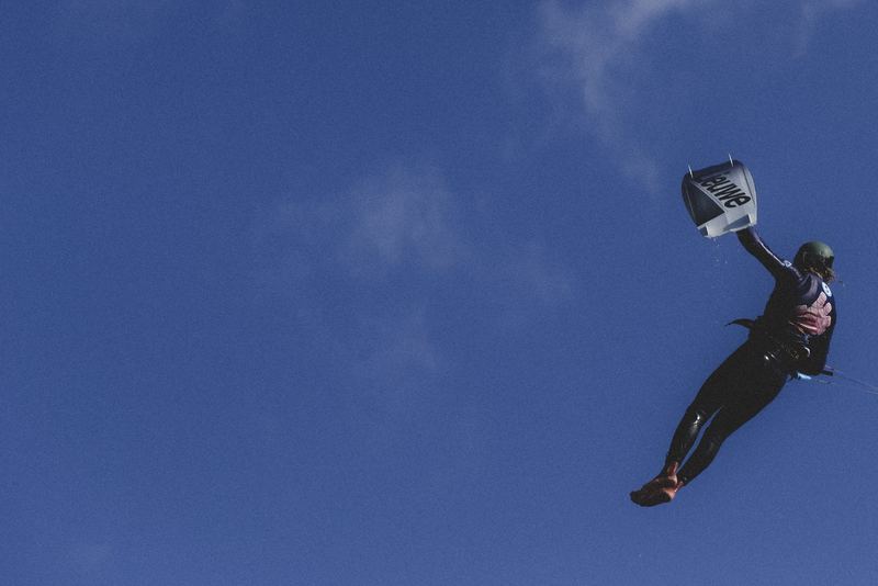 A kitesurfer suspended under the kite against deep blue sky