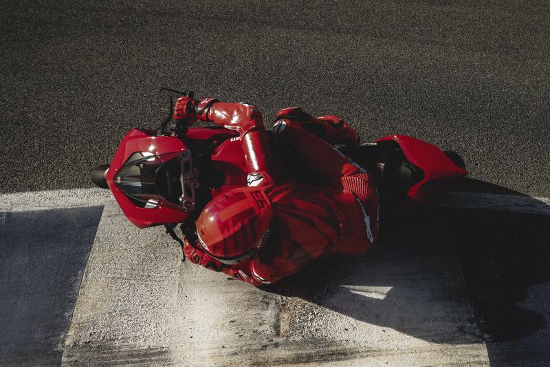 A MotoGP rider in red leathers crouched low over the bike on the tarmac