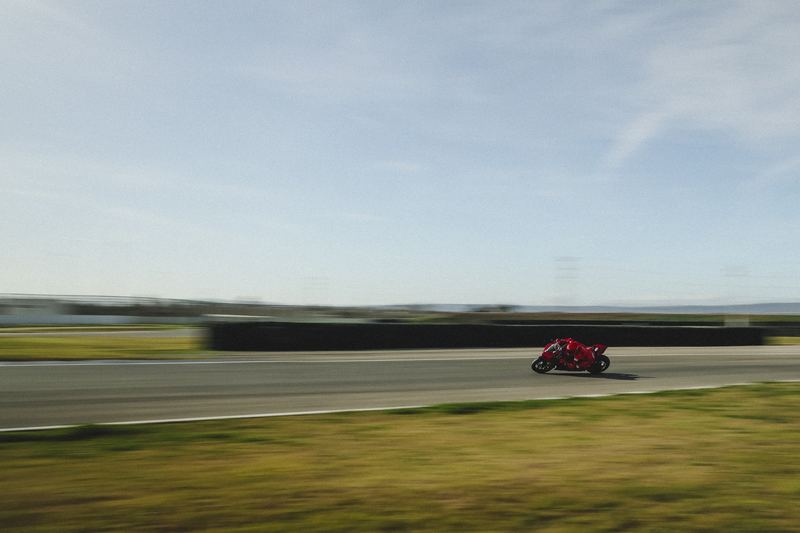 A race bike blurred to a streak along a circuit straight