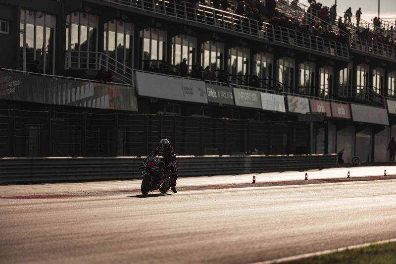 A lone motorcycle on the pit straight below the empty grandstands