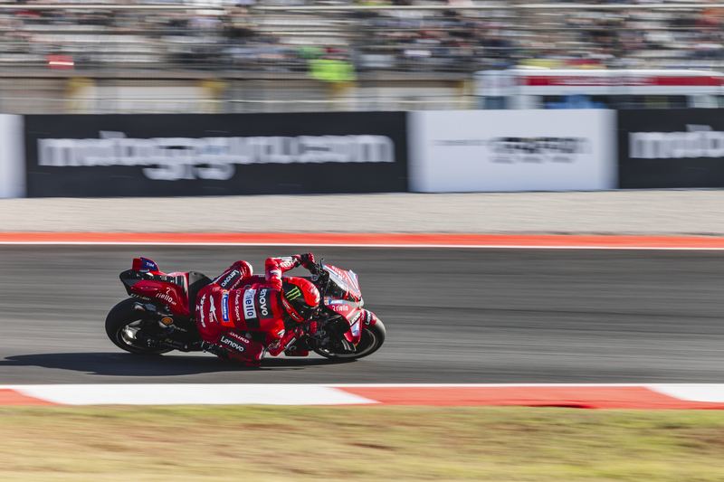 A MotoGP Ducati at full lean past the trackside boards