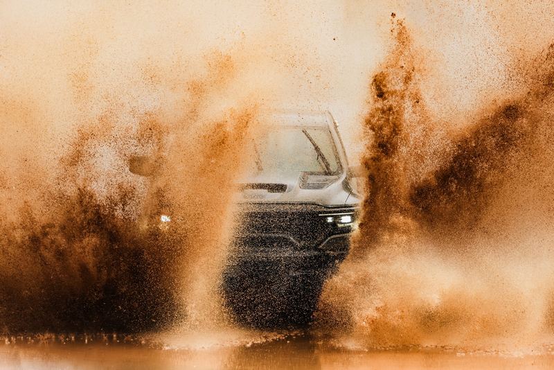 A car bursting through a wall of orange sand
