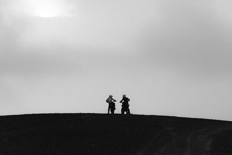 Two figures silhouetted on a ridge in fog