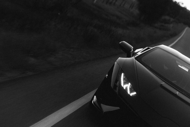 The rear haunch of a black Lamborghini on the move