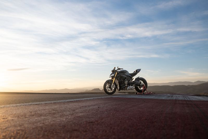 A naked motorcycle parked against a coastal sunset
