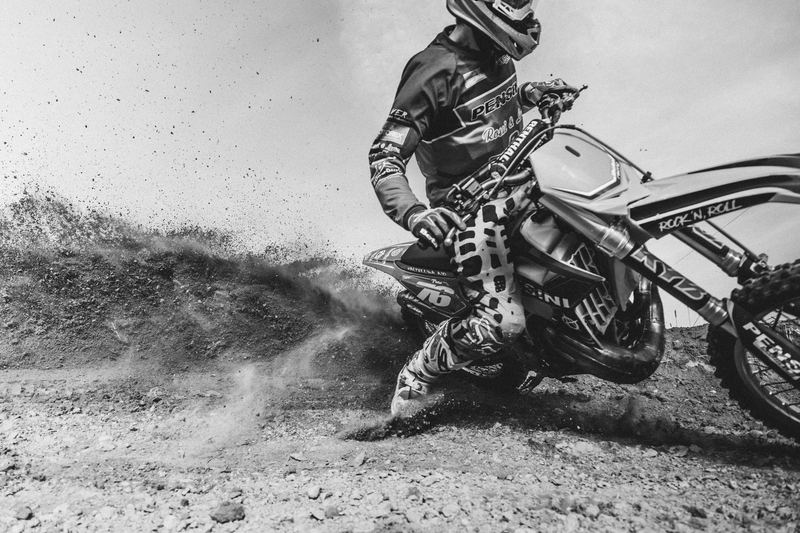 A motocross rider throwing a roost of dirt, black and white