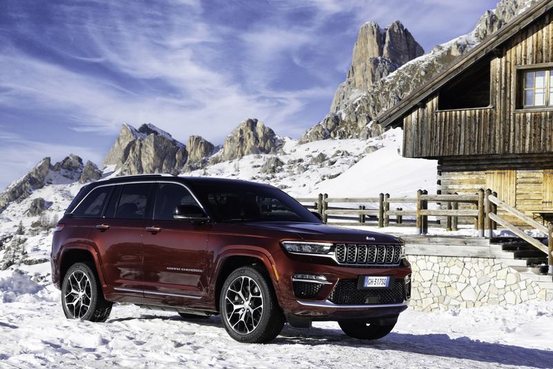 A Jeep Grand Cherokee parked in snow below dolomite peaks