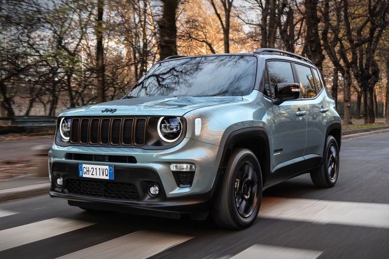 A Jeep Renegade on a road through autumn woods