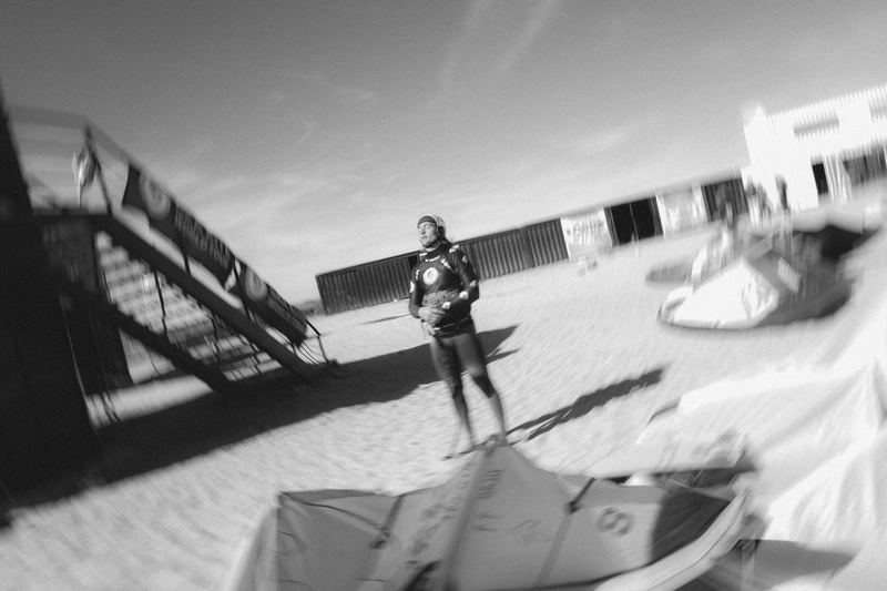 A kiter walking the shoreline past rigged kites