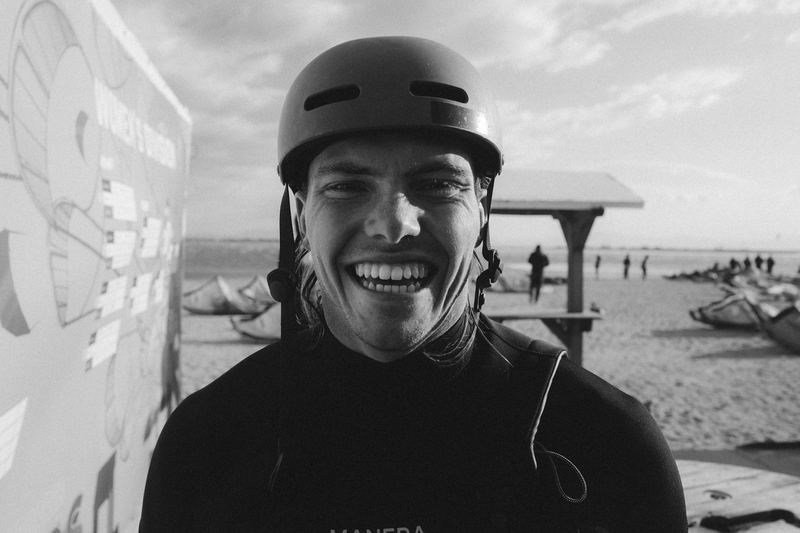 A kitesurfer laughing in a helmet on the beach