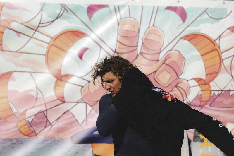 A kiter standing in front of a painted mural wall