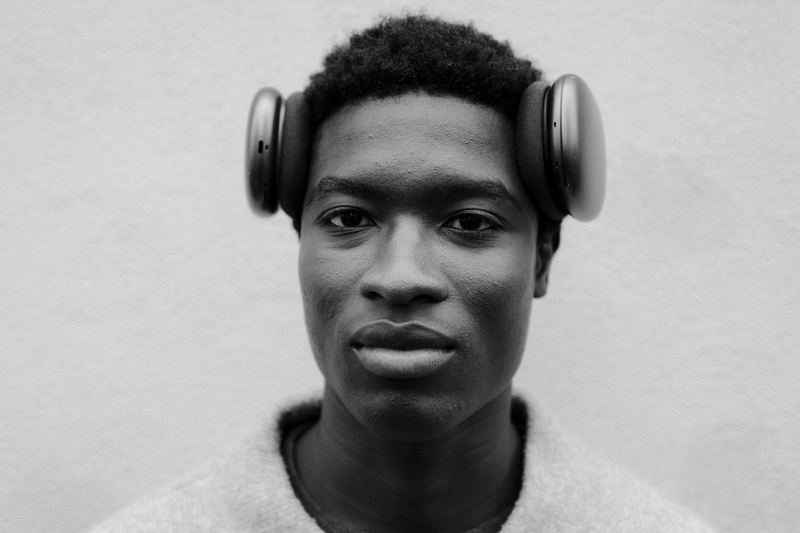 A studio portrait of a young man wearing over-ear headphones