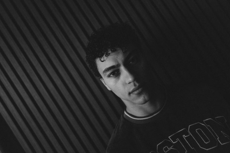 A young man against a dark ridged wall