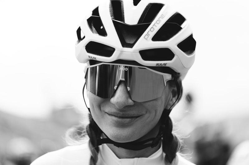 A cyclist in a white helmet and shield glasses